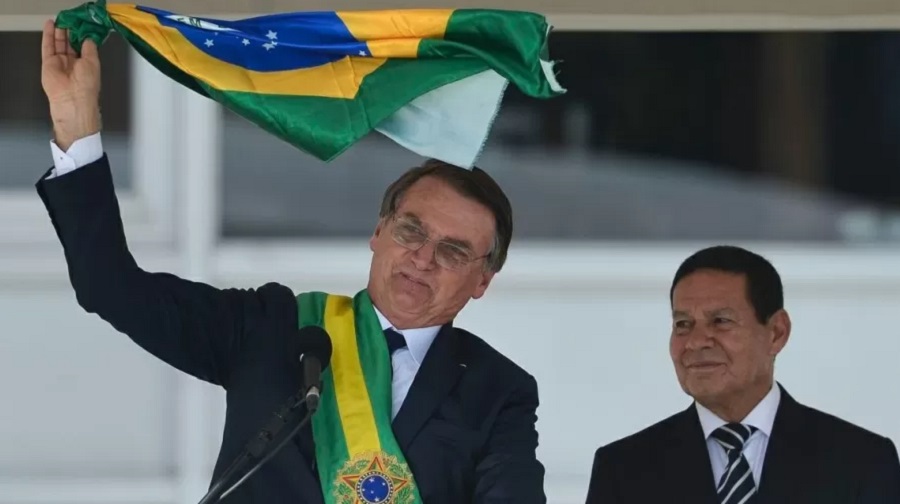 Bolsonaro e o vice-presidente Hamilton Mourão exibem uma bandeira nacional durante discurso no parlatório do Palácio do Planalto
